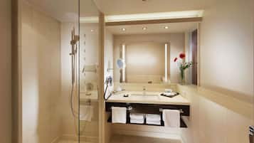 Ein modernes Badezimmer mit einer begehbaren Glasdusche, einem Waschtisch mit Spiegel und einem Waschbecken.