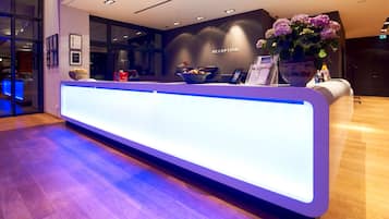 A reception desk with a modern design, a large vase of flowers, and a sign indicating the reception area.