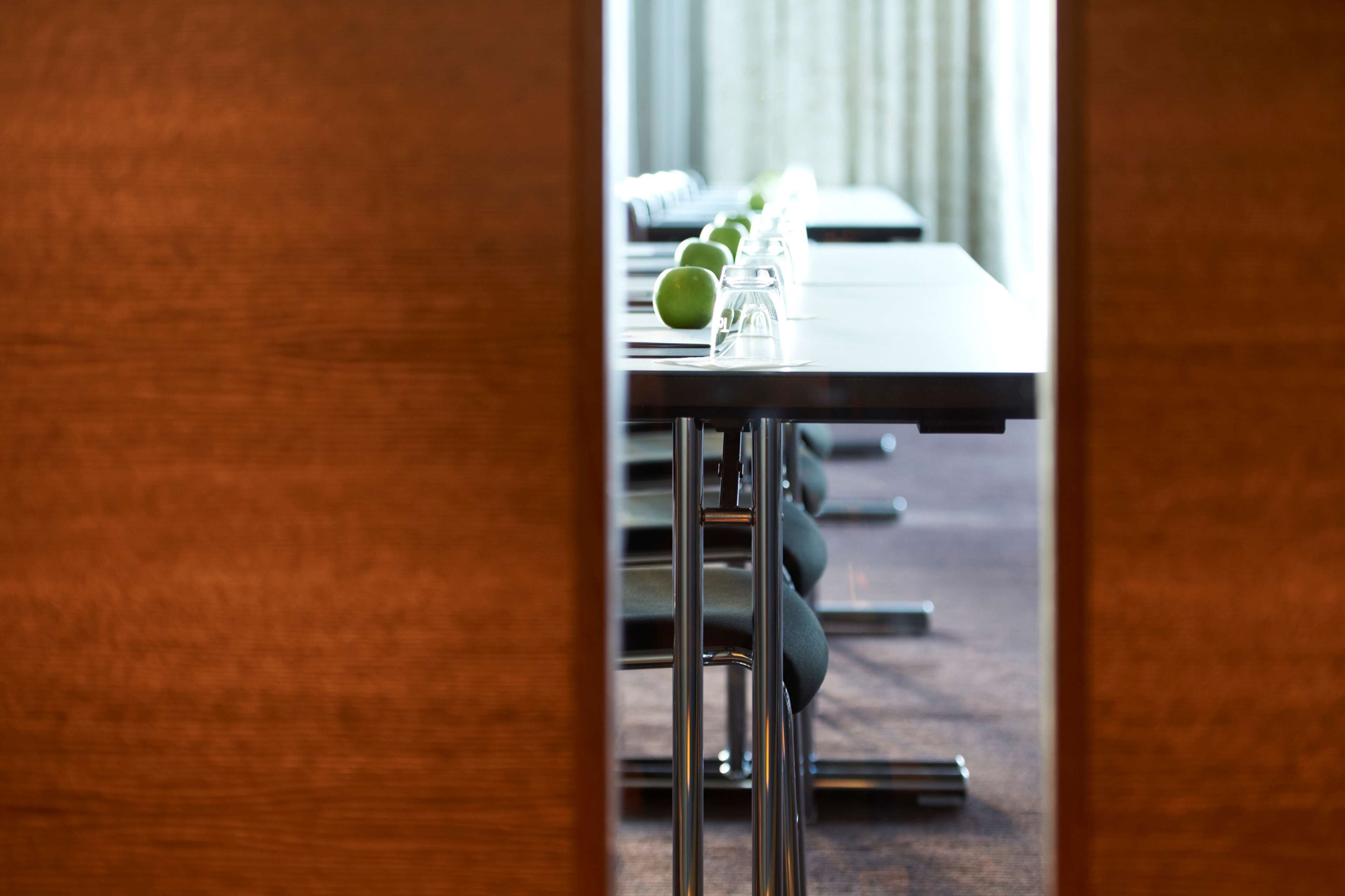 A conference table with chairs, a glass of water, and a green apple.