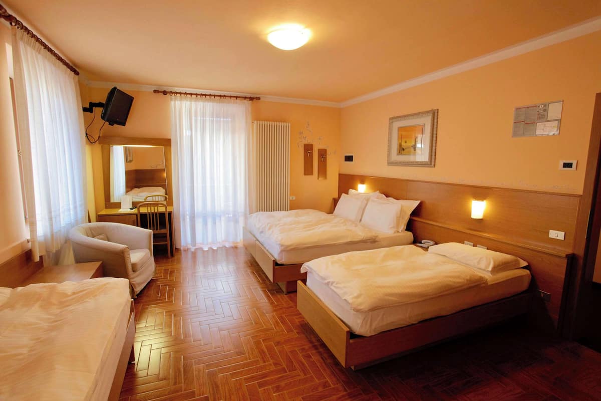 Habitación de hotel con dos camas, una silla, un escritorio y un televisor.