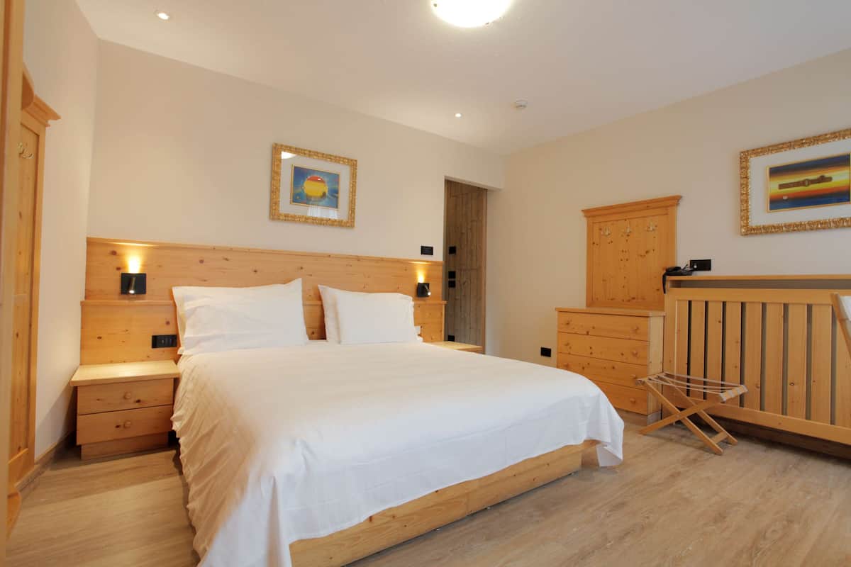 Un dormitorio con cama de madera, mesitas de noche, armario de madera y un tendedero de madera.