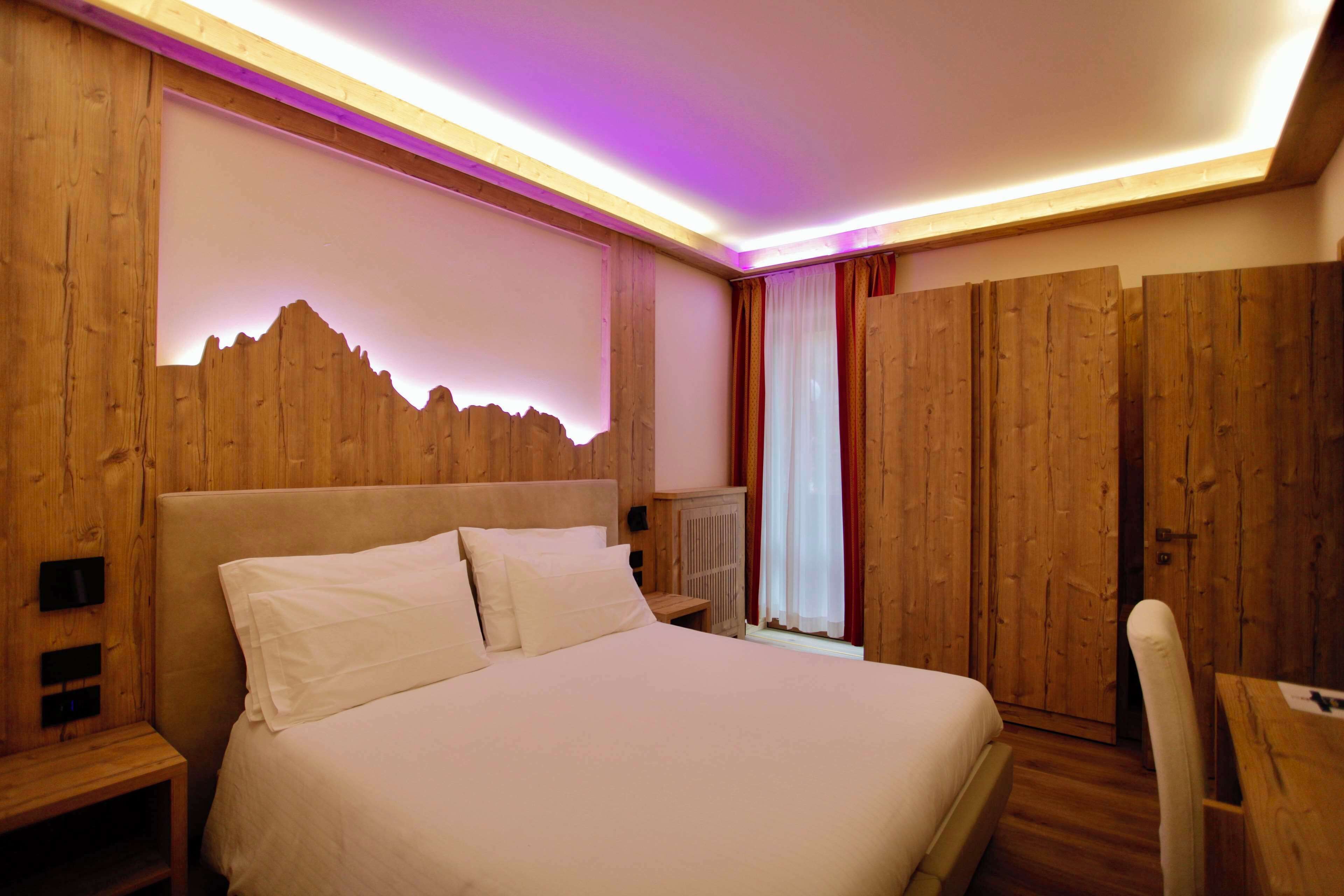 A wooden-paneled bedroom with a bed, bedside tables, and a desk.