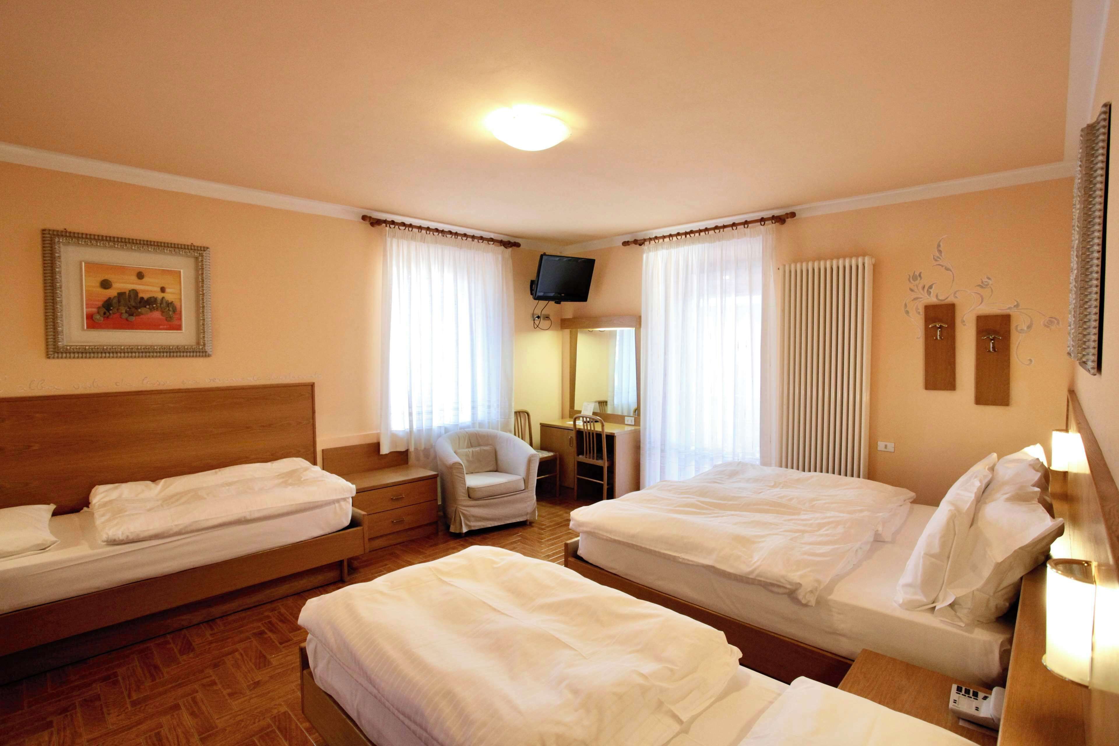 Una camera d'albergo con due letti, una scrivania, una sedia, una televisione e un quadro appeso al muro.