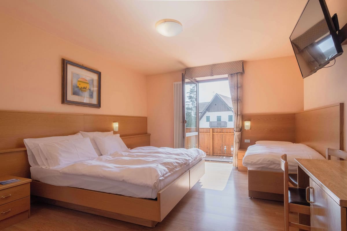 Habitación de hotel con cama, escritorio, silla, televisor y ventana con vista a un edificio.