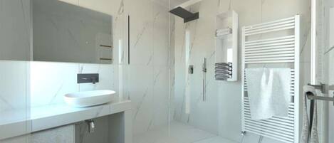 Une salle de bain moderne avec un lavabo blanc, une cabine de douche en verre et un porte-serviettes.