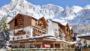 A multi-story hotel with wooden balconies and a ski resort backdrop.