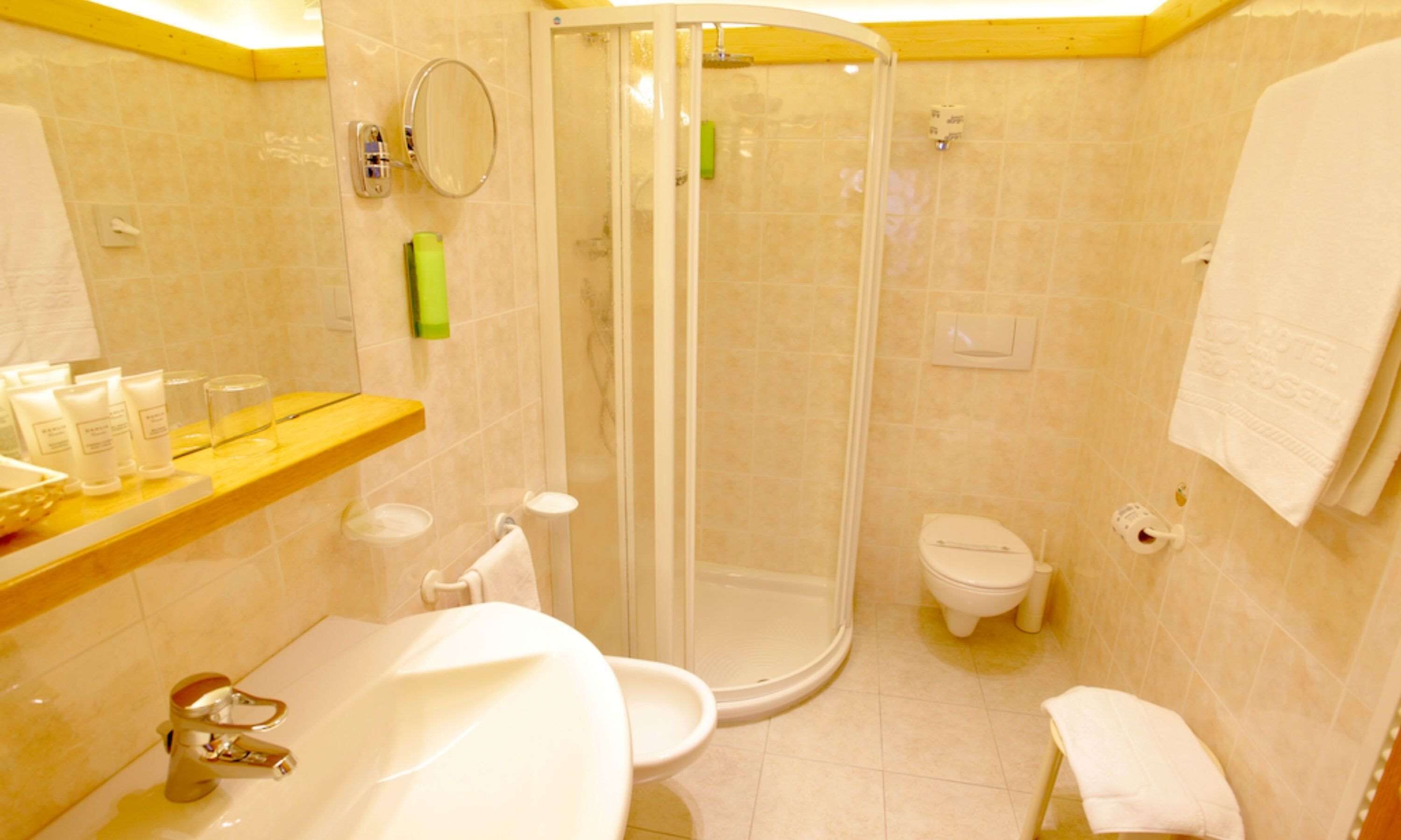 Un baño con ducha, inodoro, lavamanos y espejo.