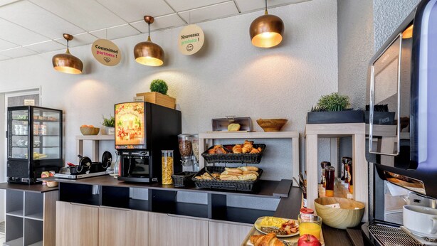 Eine moderne Frühstückstheke mit einer Kaffeemaschine, einem Fernseher und verschiedenen Speisen.