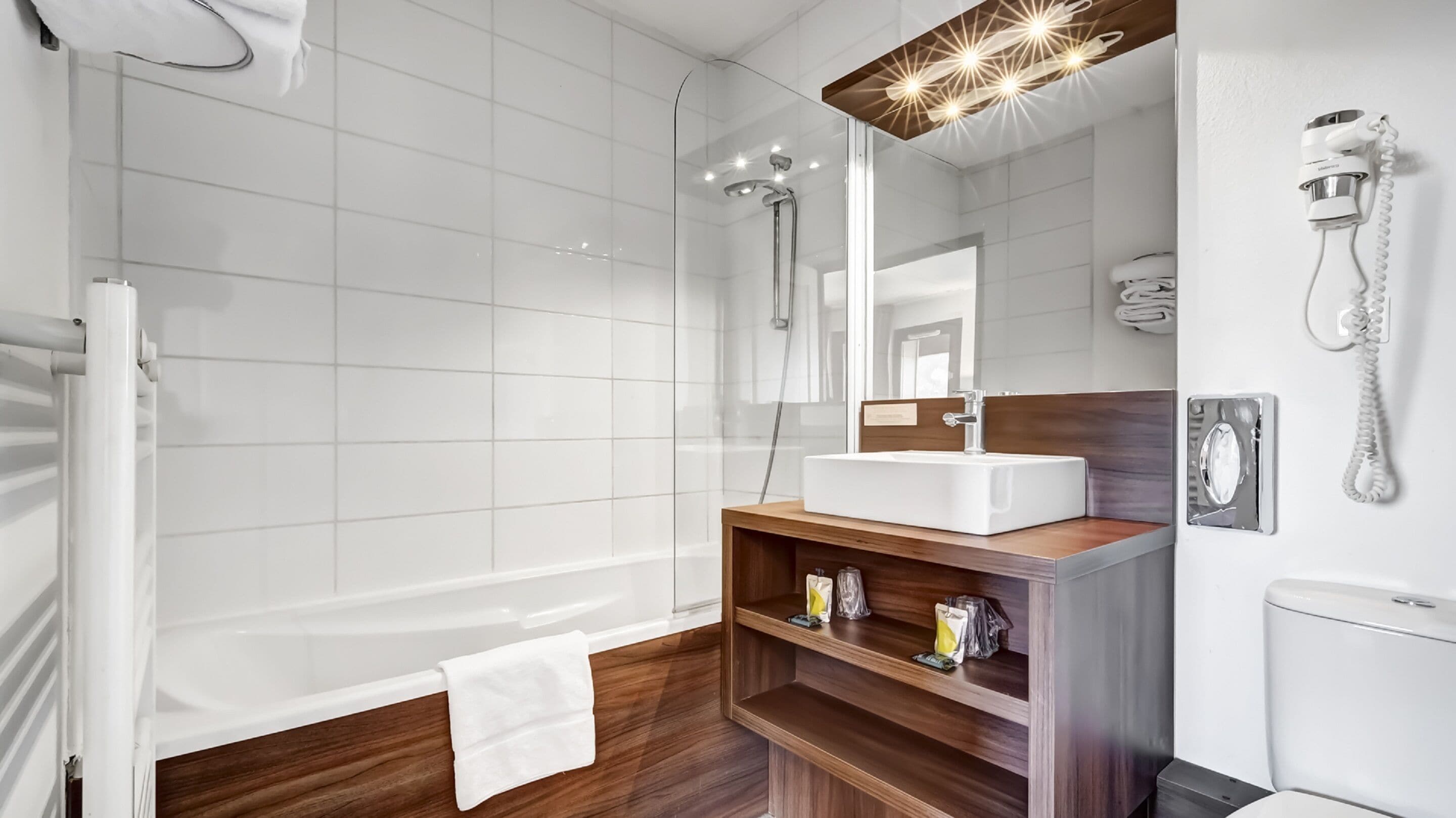 A modern bathroom with a glass-enclosed shower, a wooden vanity with a sink, and a mirror above it.