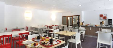 A modern dining area with multiple tables and chairs, a kitchen area, and a counter with various food items.