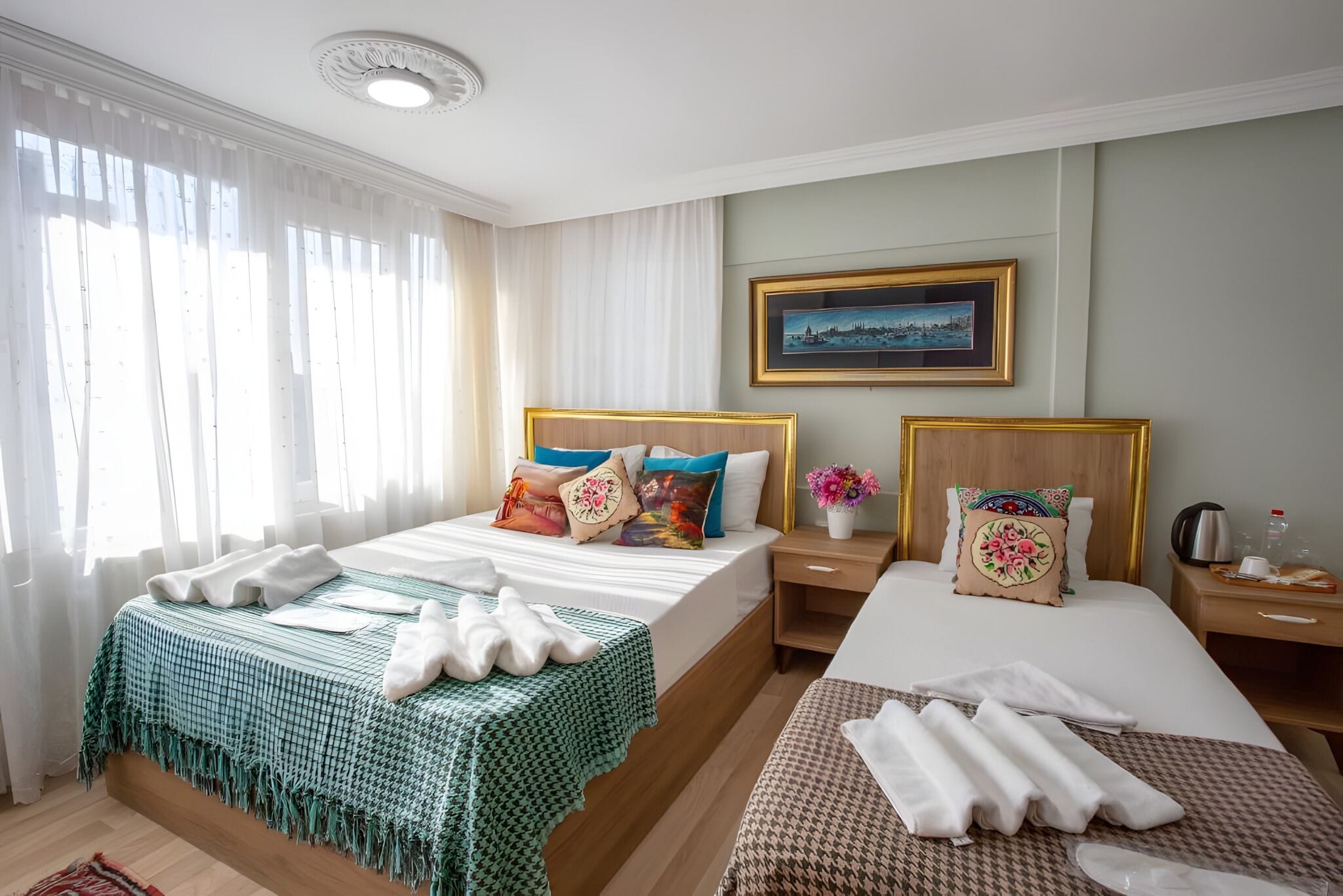 A hotel room with a large bed, a smaller bed, a nightstand with a lamp, and a painting on the wall.