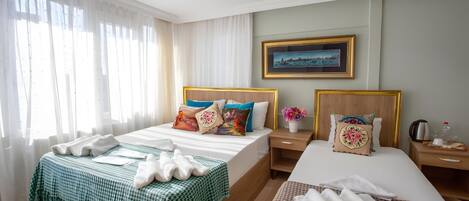 A hotel room with a large bed, a smaller bed, a nightstand with a lamp, and a painting on the wall.
