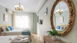 A hotel room with two beds, a large ornate mirror, a wooden dresser, and a potted plant. - Sofia Corner Hotel (Istanbul)