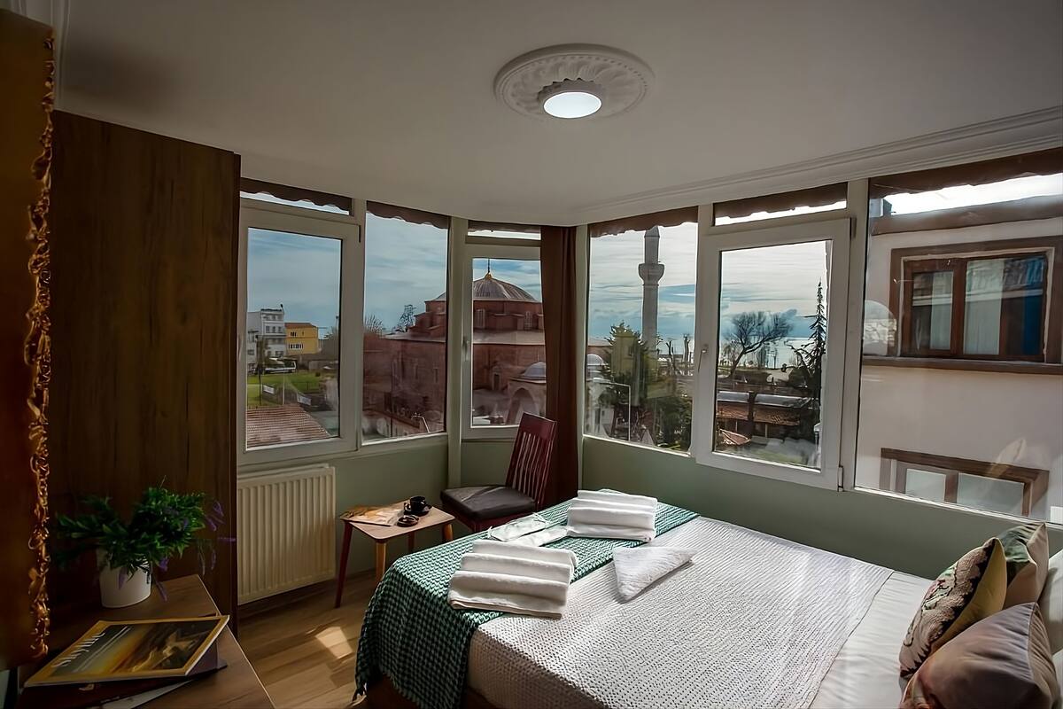 Ein Hotelzimmer mit einem großen Bett, einem Sessel, einem kleinen Tisch und einer Topfpflanze.