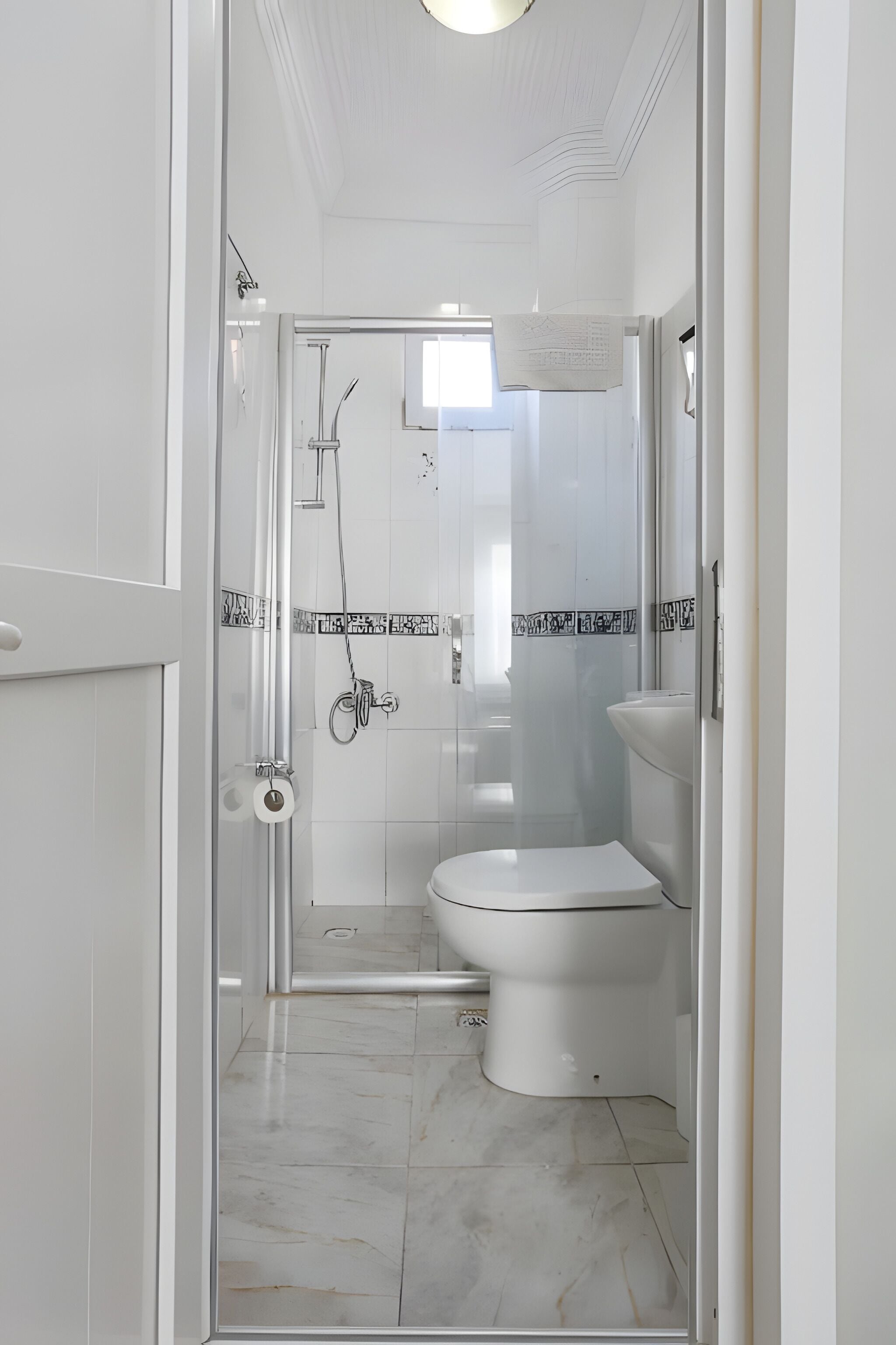 A bathroom with a glass shower enclosure, a toilet, and a sink.