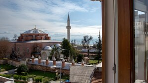 A view of a mosque with a tall minaret and a dome, surrounded by greenery and buildings. - Sofia Corner Hotel (Istanbul)