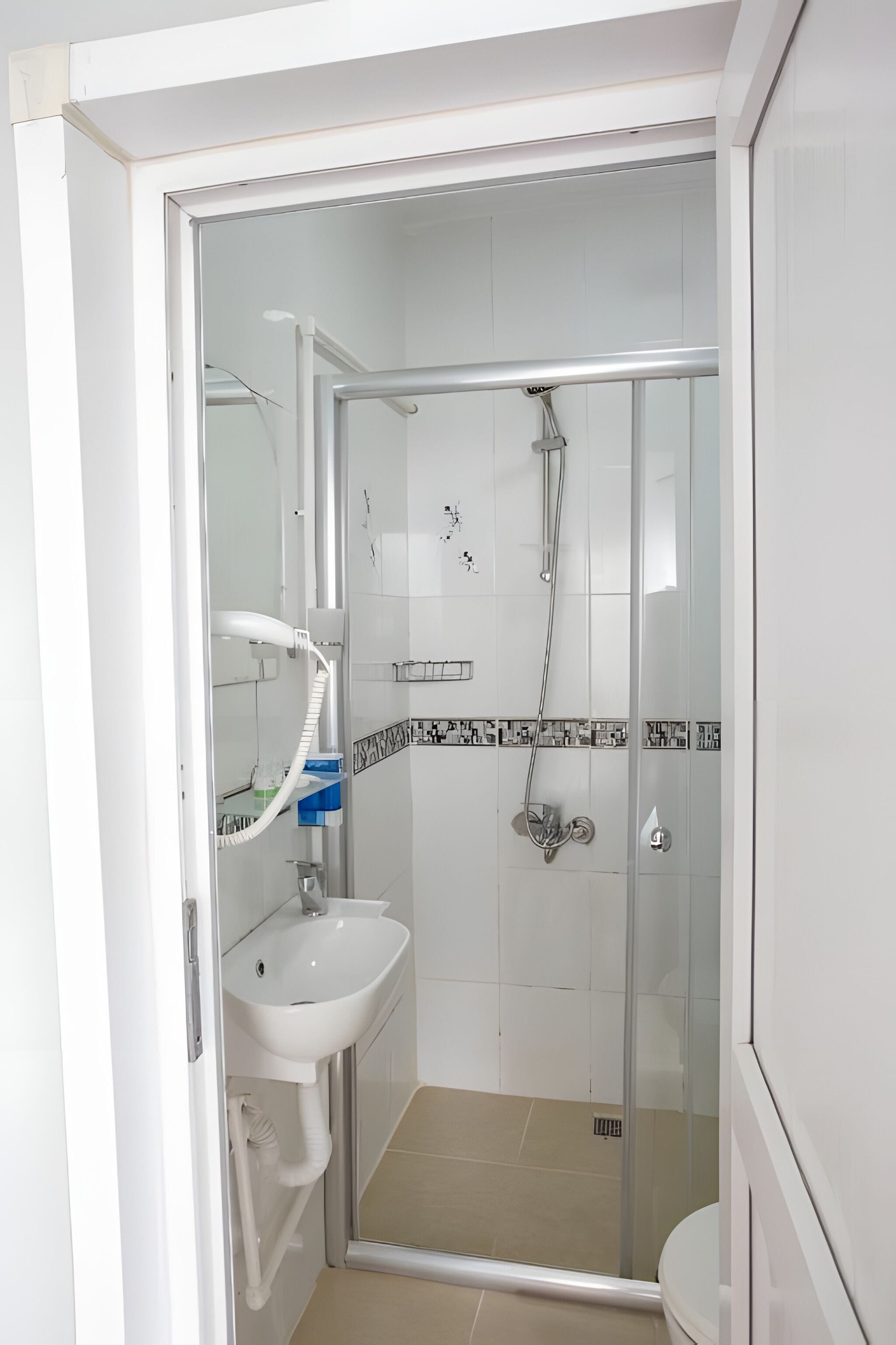 A modern bathroom with a glass-enclosed shower, a white sink, and a toilet.
