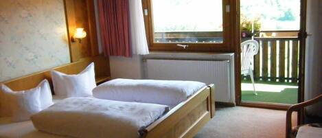 A double bed with wooden headboard, a window with a view of a balcony, and a radiator.
