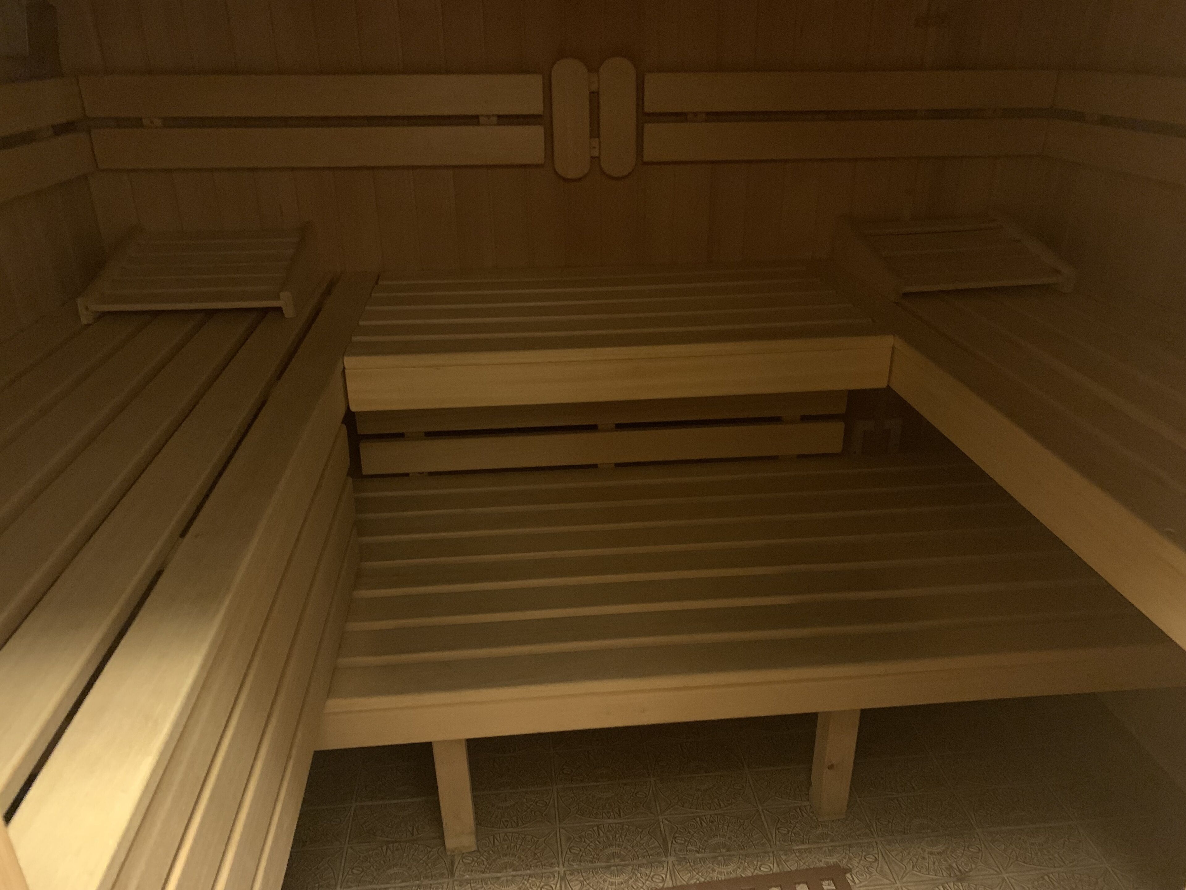 A sauna with wooden benches and a tiled floor.