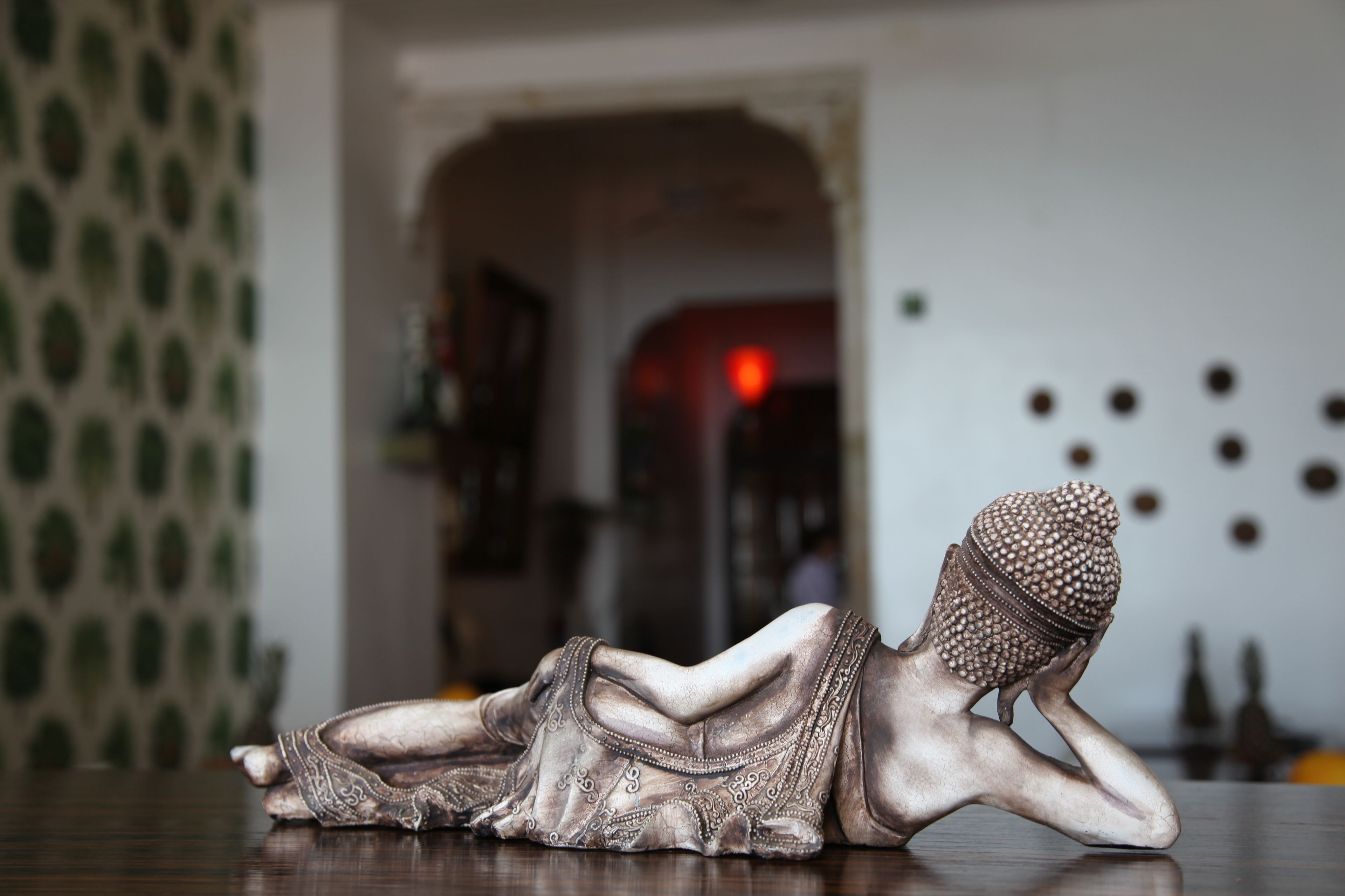 Una estatua de una figura sentada con un velo para la cabeza, sobre una superficie de madera.