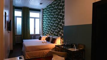 A hotel room with a large bed, a desk with a chair, and a window with curtains.