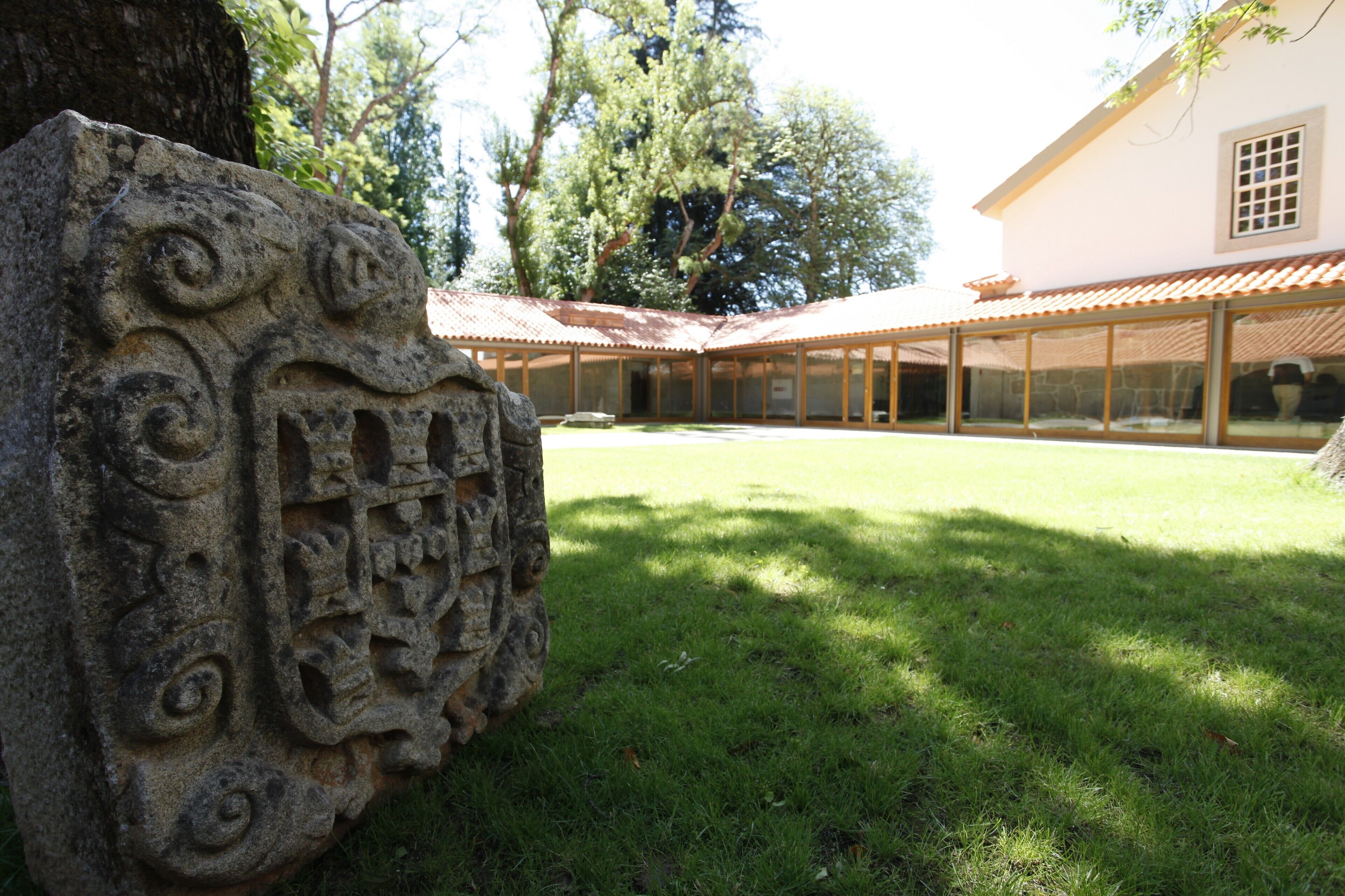 Un patio con un grabado de piedra, un edificio con tejado de azulejos y un árbol.