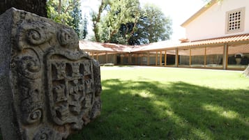 Un patio con un grabado de piedra, un edificio con tejado de azulejos y un árbol.
