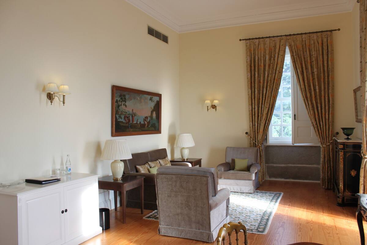 A living room with a sofa, armchairs, a coffee table, and a painting on the wall.