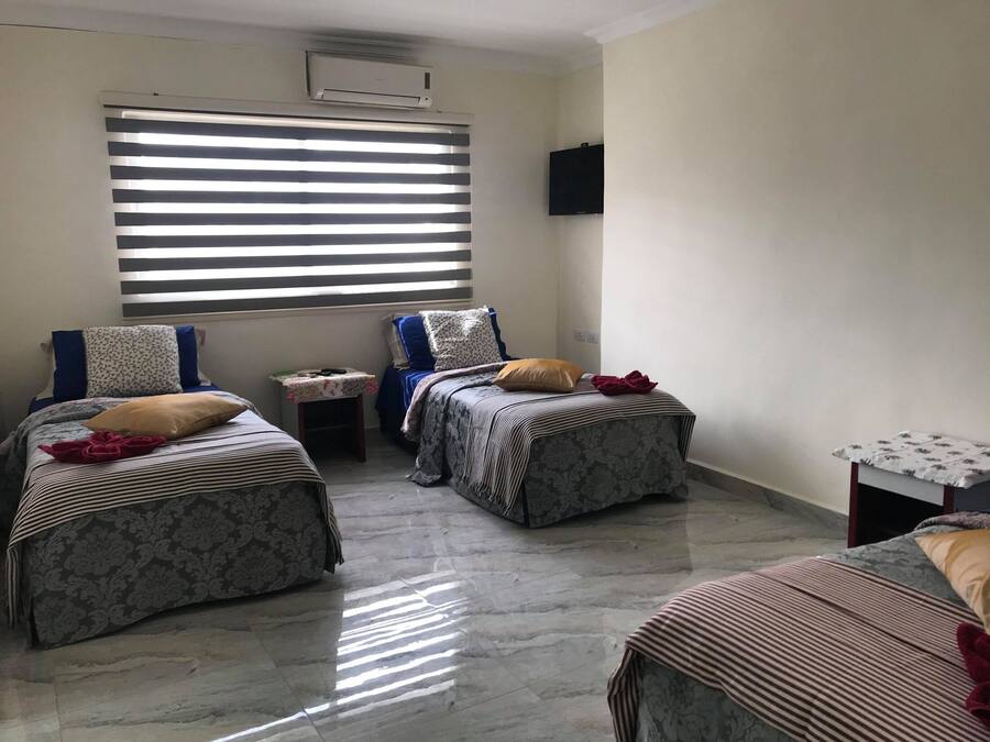 Una habitación con dos camas, una mesita pequeña y un televisor instalado en la pared.
