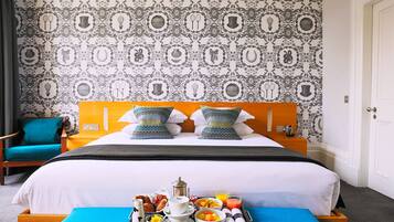 Una habitación de hotel con una cama, una bandeja de desayuno y un papel tapiz estampado.