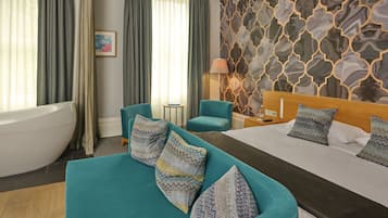 Una habitación de hotel moderna con una cama grande, un sofá, una bañera y un papel tapiz estampado.