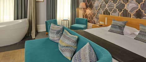 Una habitación de hotel moderna con una cama grande, un sofá, una bañera y un papel tapiz estampado.