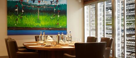 A dining area with a round table, chairs, and a painting on the wall.
