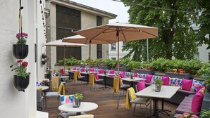 An outdoor patio area with seating arrangements, tables, and hanging planters. - Malmaison Cheltenham (Cheltenham)