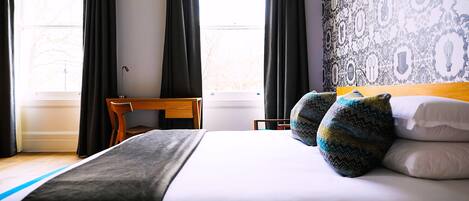 A hotel room with a bed, a desk, and a chair.