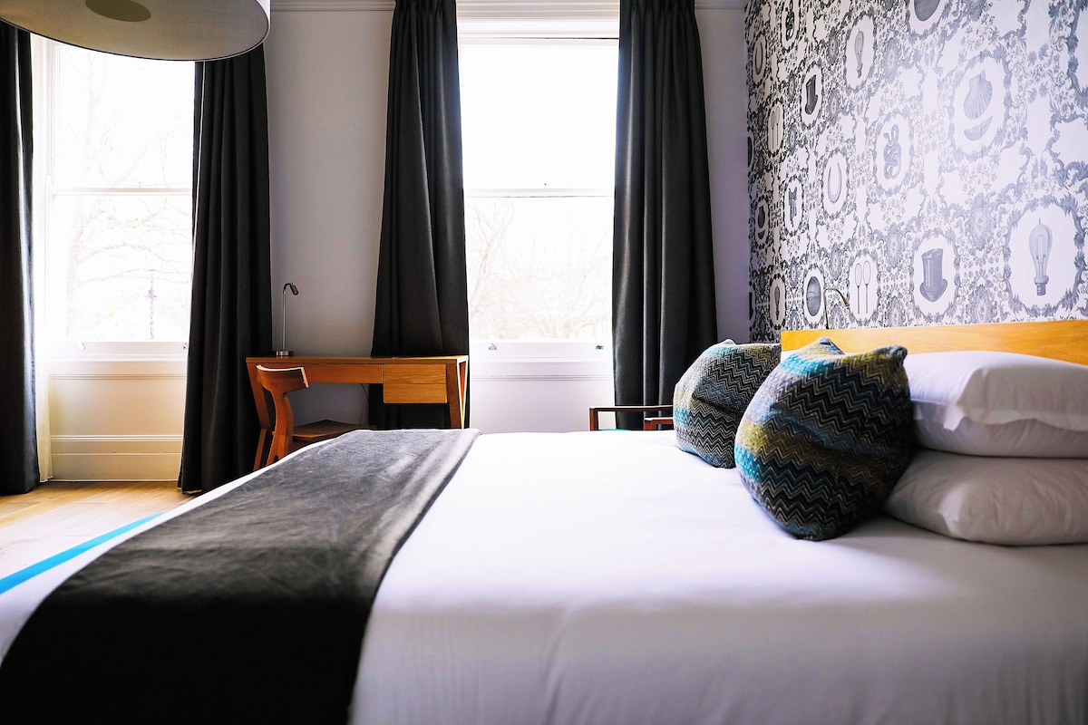 A hotel room with a bed, a desk, and a chair.