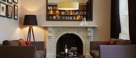 Una sala de estar con dos sofás, una chimenea, una estantería y un espejo grande.