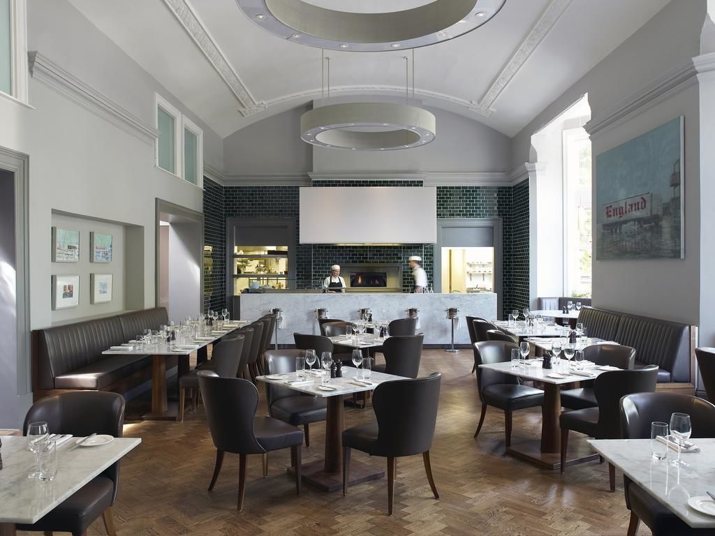 Un restaurant doté d’un bar central, de banquettes et d’un plafond haut orné de luminaires circulaires.