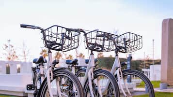 Three bicycles parked on a grassy area with a clear sky in the background.