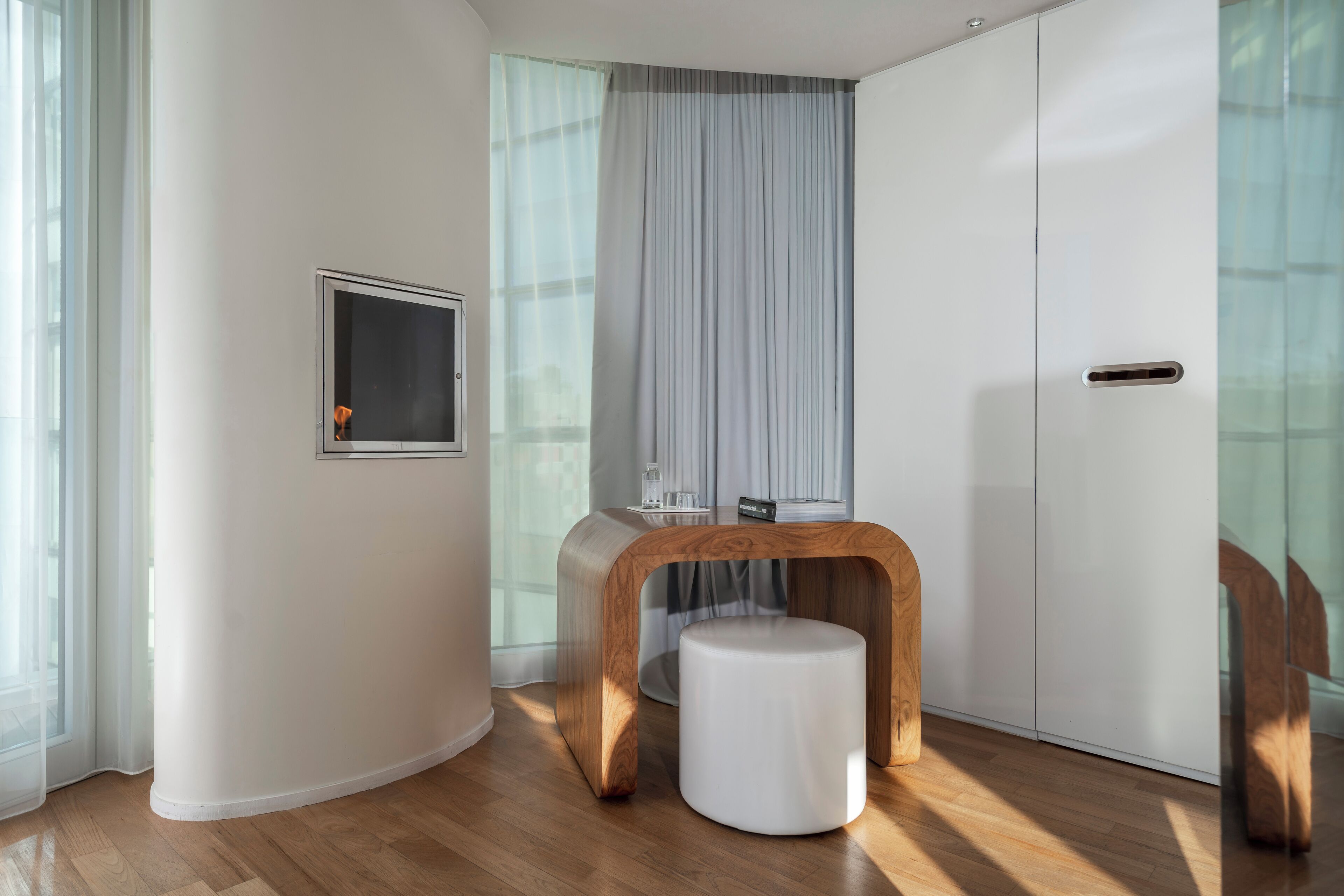 Une pièce moderne avec une table en bois, un tabouret blanc, une vitrine et une porte coulissante.