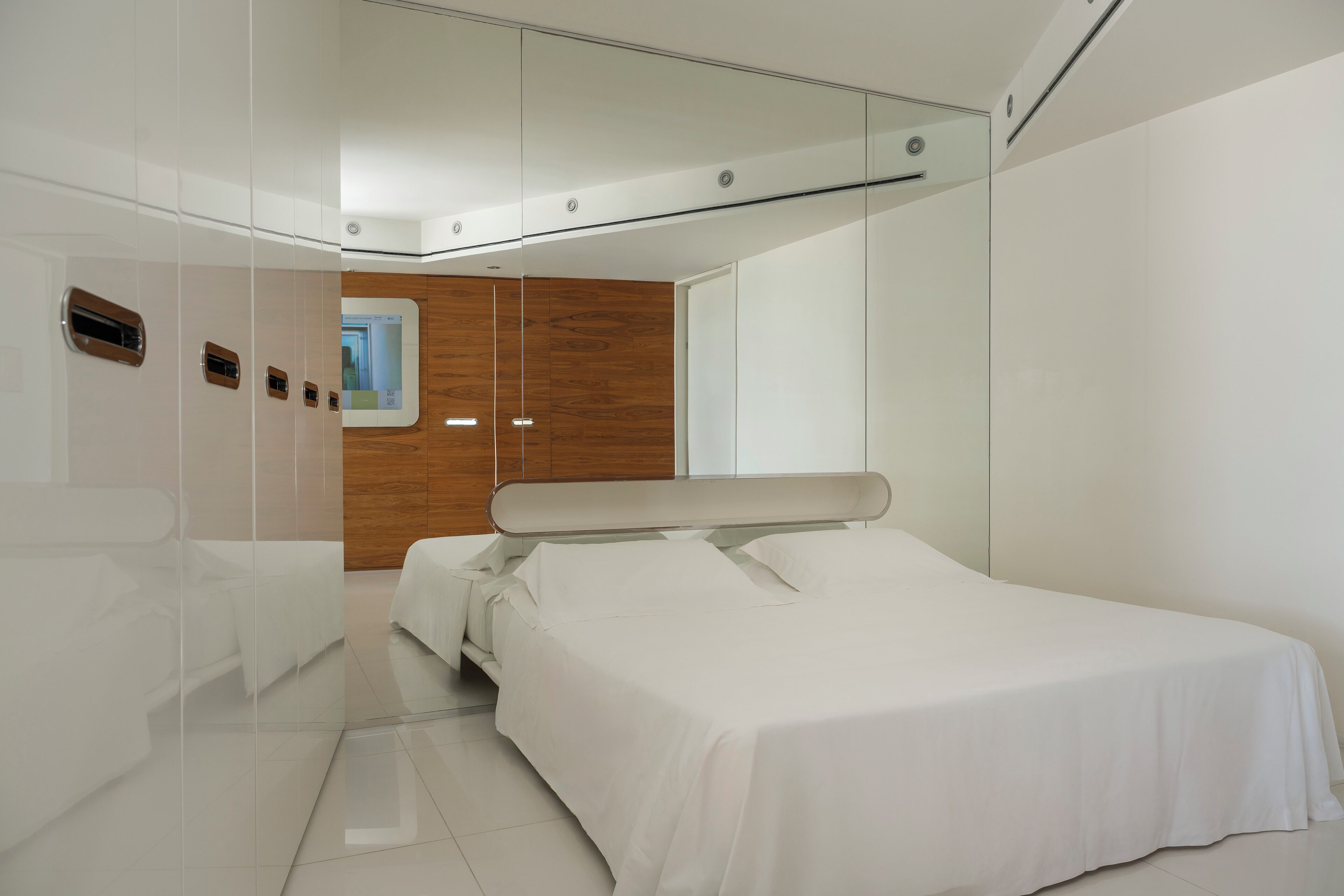 Une chambre à coucher moderne avec un grand lit, un mur d’accent en bois et un miroir.
