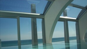 A modern room with large floor-to-ceiling windows offering a view of the ocean.