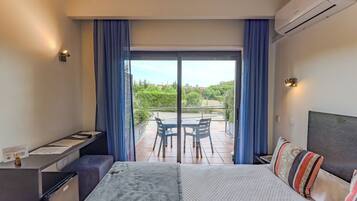 A hotel room with a bed, a desk, a chair, and a view of the outdoors.