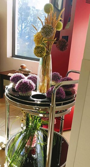 A round metal stand with a vase of flowers and a small table with a decorative item. - Casa Do Vale Hotel (Évora)