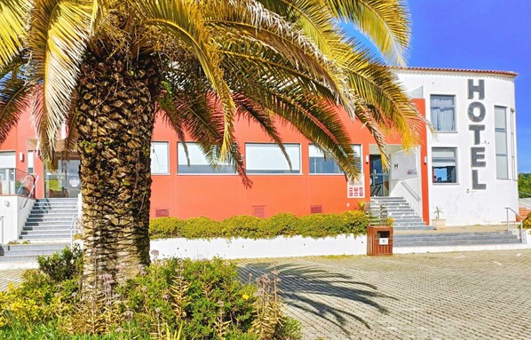 Un hotel con facciata rossa, pareti esterne bianche e un cartello con la scritta 'HOTEL'.