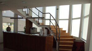 A spacious kitchen with a central island, a wooden staircase, and large windows. - Casa Do Vale Hotel (Évora)