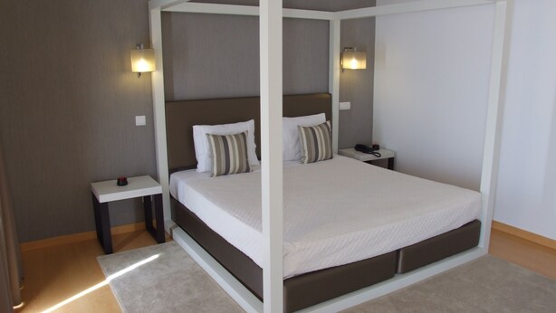 A four-poster bed with a white frame, two bedside tables, and a bedside lamp on each side. - Casa Do Vale Hotel (Évora)