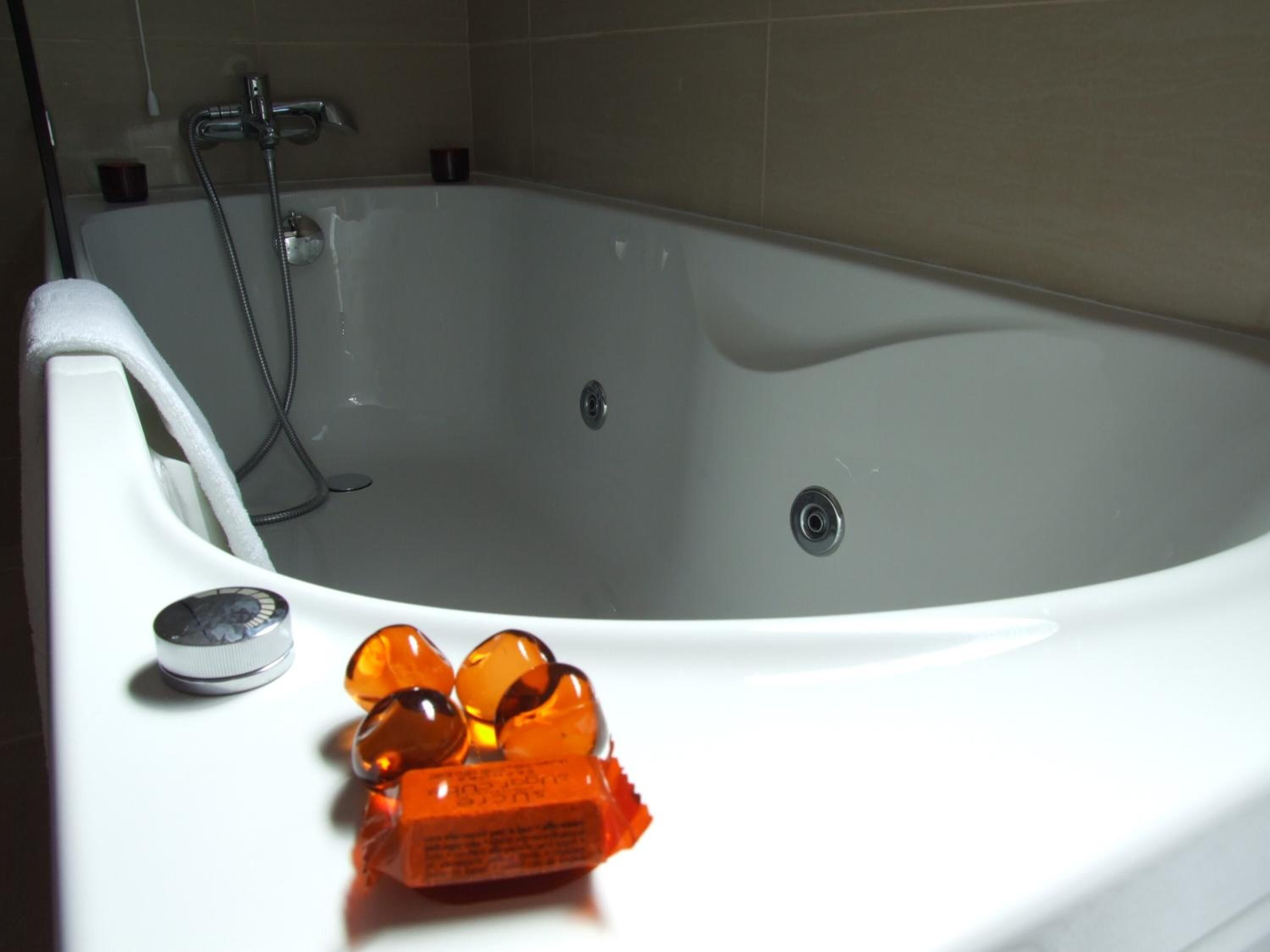 A bathtub with a handheld showerhead and a bottle of shampoo.