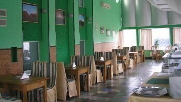 A dining area with green walls, multiple tables, and chairs. - Hotel Volter (Lviv)