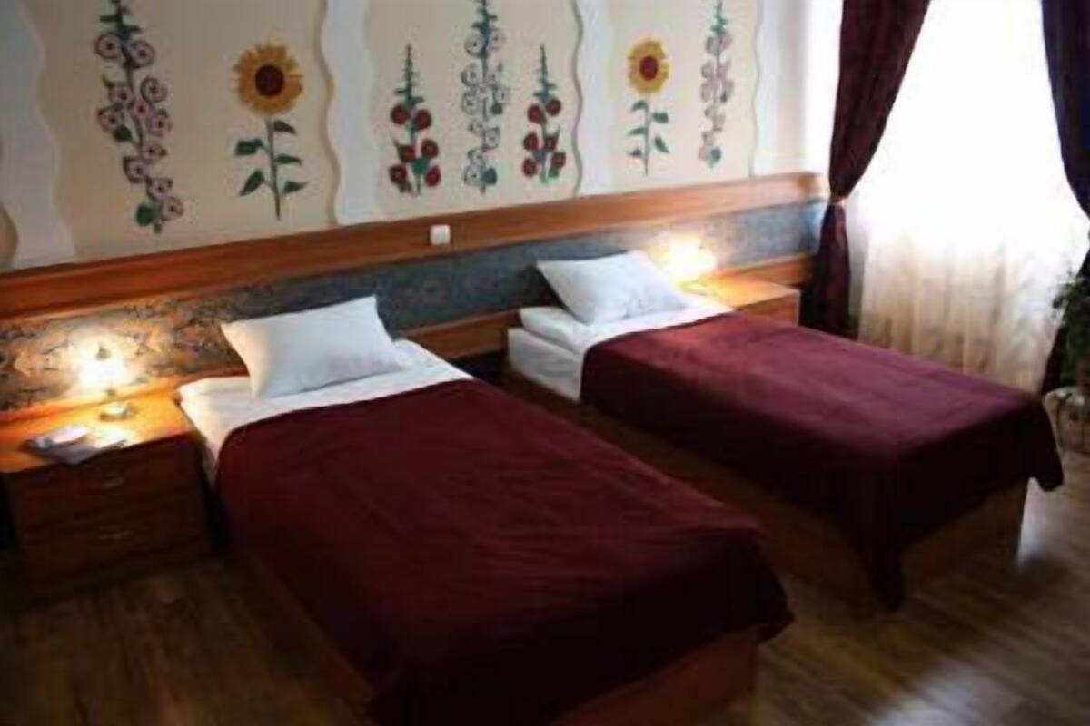 Una habitación de hotel con dos camas individuales, cabecero de madera y decoración floral en las paredes.